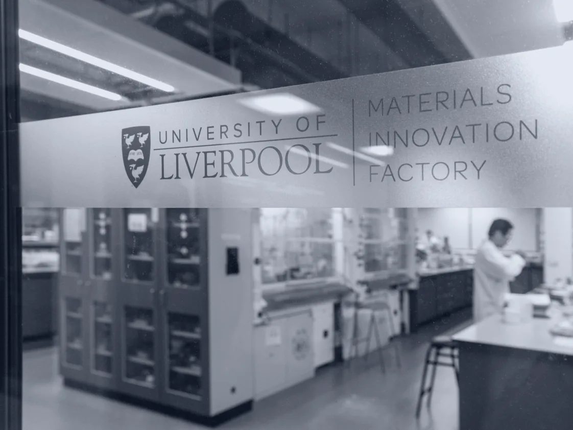 A laboratory at the Materials Innovation Factory, seen through glass etched with the University of Liverpool and Materials Innovation Factory names.